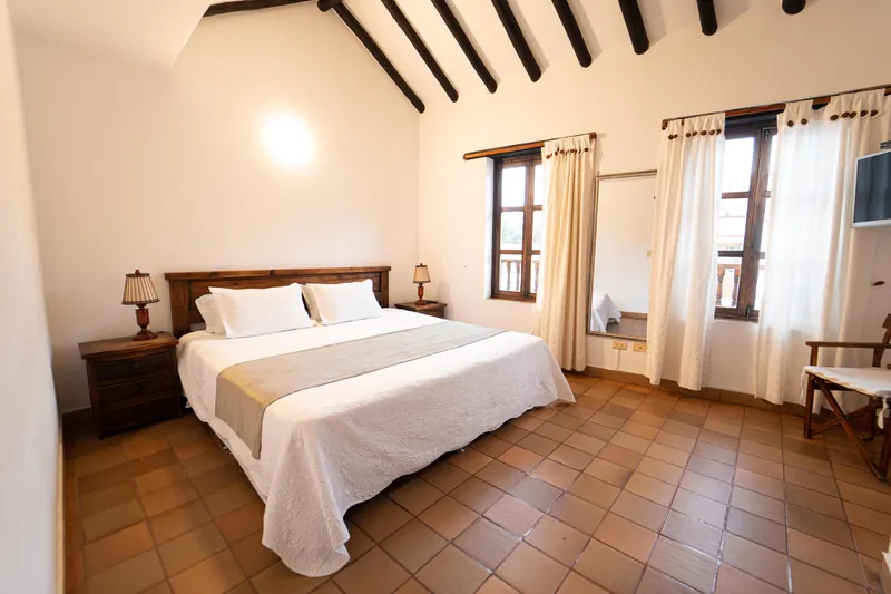 Habitación San Francisco con cama King, vigas de madera y cortinas blancas