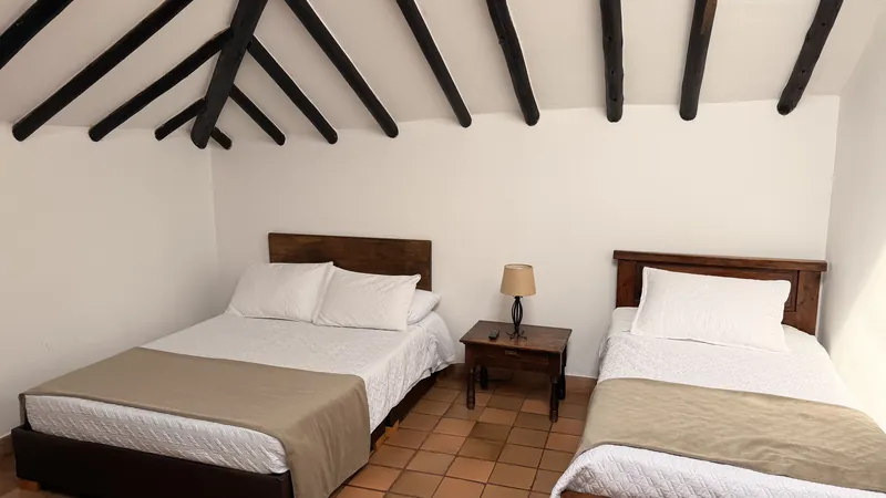 Habitación San Rafael con cama doble, cama sencilla y techo de vigas de madera